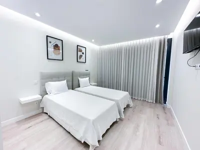 a white bedroom with two beds and a television at Villa Montana in São Vicente
