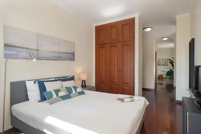 a bedroom with a large white bed with blue pillows at Apartamento do Carmo by An Island Apart in Funchal