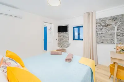 a white bedroom with a bed and a desk at Chalé Henrique - Beachfront apartments at Calheta Beach in Calheta