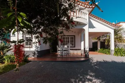 a white house with a table and chairs on a porch at GuestReady - Peaceful Paradise in Madeira in Arco da Calheta