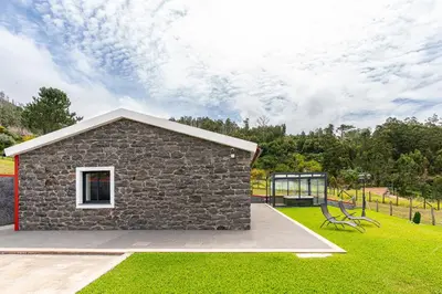 a stone building with a bench in the grass at Florenças House - Private Jacuzzi & Garden in Calheta