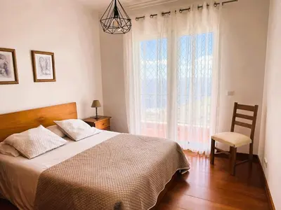 a bedroom with a bed and a chair and a window at Vista Reis Magos in Caniço