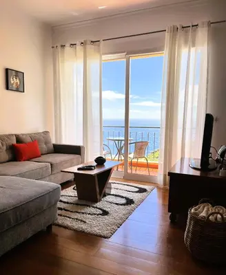 a living room with a couch and a view of the ocean at Vista Reis Magos in Caniço