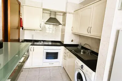 a kitchen with white cabinets and a sink at Vista Reis Magos in Caniço