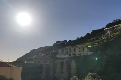 a building on a hill with houses on it at Comfy apt in the heart of Ponta do Sol in Ponta do Sol