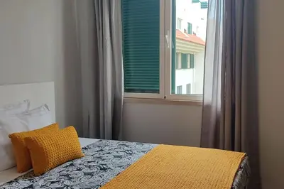 a bedroom with a window and a bed with a yellow blanket at Comfy apt in the heart of Ponta do Sol in Ponta do Sol
