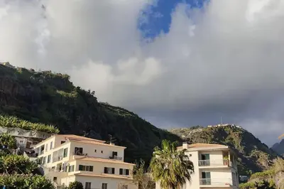a group of buildings in front of a mountain at Comfy apt in the heart of Ponta do Sol in Ponta do Sol