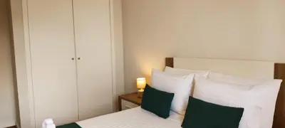a bedroom with a bed with green and white pillows at Sol e Mar in Ponta do Sol