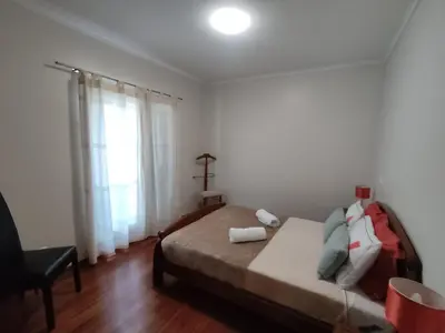 a bedroom with a bed and a chair and a window at Sol e Mar in Ponta do Sol