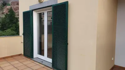 a door with green shutters on a building at Sol e Mar in Ponta do Sol