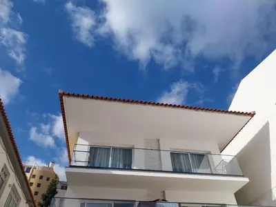 a white building with a balcony on top of it at Villa Supranee Ocean View in Câmara de Lobos