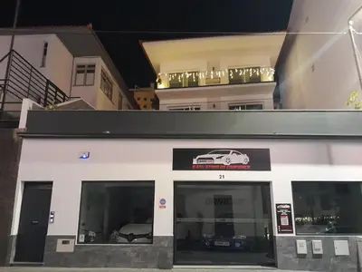 a white building with a car sign on it at Villa Supranee Ocean View in Câmara de Lobos