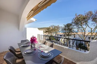 a table on a balcony with a view of the ocean at Casa Jóia in Luz