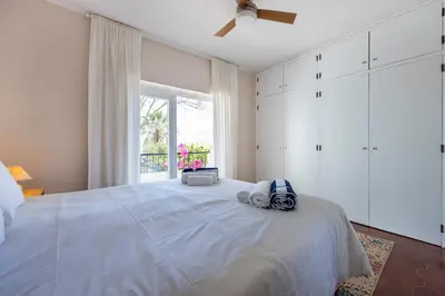 a bedroom with a large white bed with a window at Casa Jóia in Luz