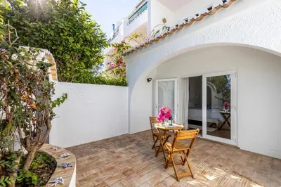 a patio with chairs and a table with flowers on it at Casa Jóia in Luz