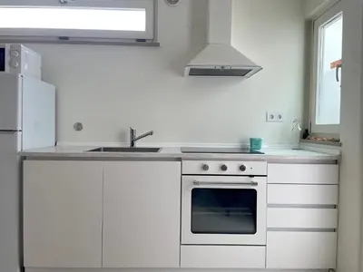 a white kitchen with a sink and a stove at Estudio Hortas in Vila do Bispo