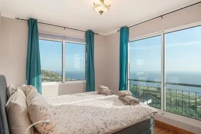 a bedroom with a bed and large windows at OurMadeira - Vista Mar in Canhas