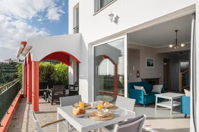 a patio with a table and chairs on a balcony at OurMadeira - Vista Mar in Canhas