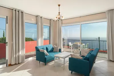 a living room with blue furniture and large windows at OurMadeira - Vista Mar in Canhas