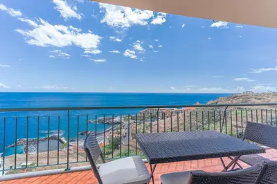 a balcony with a table and chairs and the ocean at Sunspot Reis Magos with sea view by Holiday Rental Madeira in Caniço