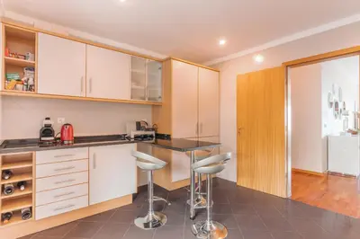 a kitchen with white cabinets and bar stools at Sunspot Reis Magos with sea view by Holiday Rental Madeira in Caniço