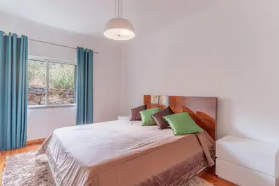 a bedroom with a bed with green pillows and a window at Sunspot Reis Magos with sea view by Holiday Rental Madeira in Caniço