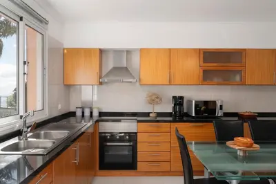 a kitchen with wooden cabinets and a glass table at Casa da Quinta Grande by An Island Apart in Câmara de Lobos