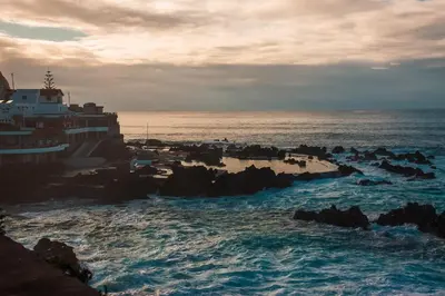 a beach with rocks and the ocean with a building at The Mountain View, By OP in São Vicente