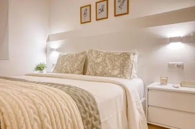 a white bedroom with a large bed and a nightstand at Pôr do Sol, a Home in Madeira in Ponta do Sol