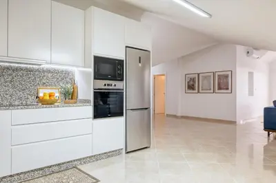 a kitchen with white cabinets and a tv on the wall at Pôr do Sol, a Home in Madeira in Ponta do Sol