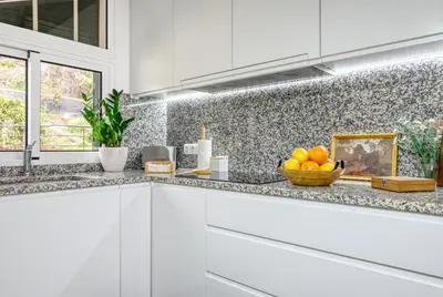 a white kitchen with a bowl of oranges on the counter at Pôr do Sol, a Home in Madeira in Ponta do Sol