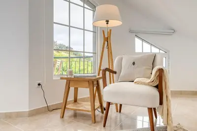 a room with a chair and a table with a lamp at Pôr do Sol, a Home in Madeira in Ponta do Sol