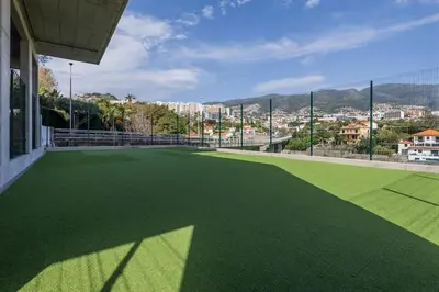 a green tennis court with a view of a city at The Place View in Funchal