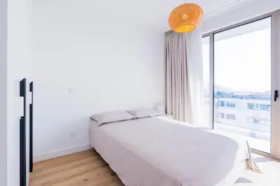 a white bedroom with a bed and a large window at The Place View in Funchal