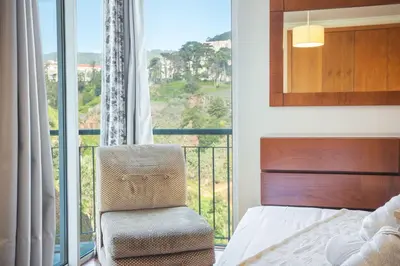 a bedroom with a bed and a chair and a balcony at Charming Garajau by AH in Caniço