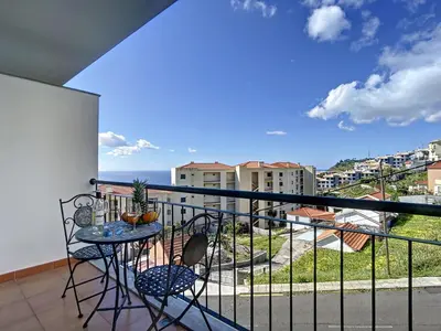 a balcony with a table and chairs and a view of the ocean at Charming Garajau by AH in Caniço