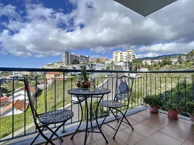 a balcony with two chairs and a table on a balcony at Charming Garajau by AH in Caniço