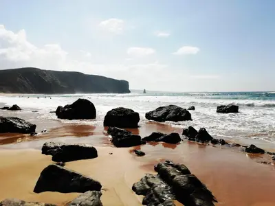 a beach with rocks in the sand and the ocean at Bela Vista_ Cozy Apartment with Sea View in Aljezur