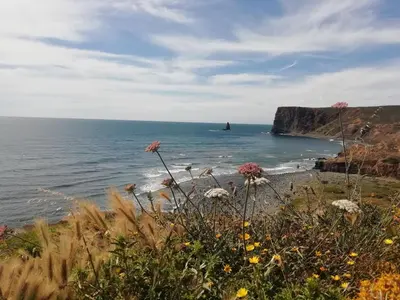 a view of the ocean with a lighthouse in the distance at Bela Vista_ Cozy Apartment with Sea View in Aljezur
