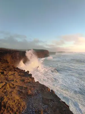 an ocean wave hitting the shore of a cliff at Bela Vista_ Cozy Apartment with Sea View in Aljezur