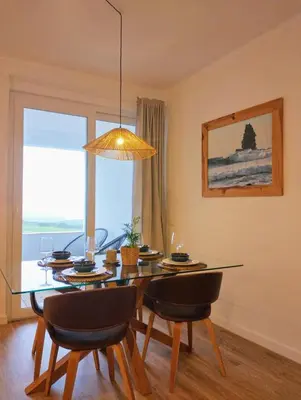 a dining room table with chairs and a large window at Bela Vista_ Cozy Apartment with Sea View in Aljezur