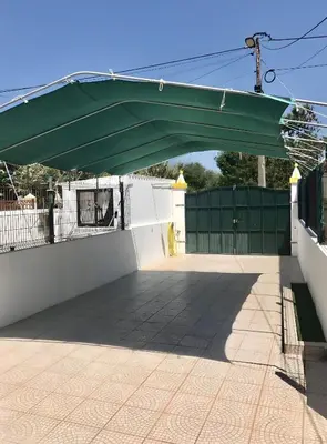 a green canopy over a white wall with a gate at Casa Sagres in Vila do Bispo