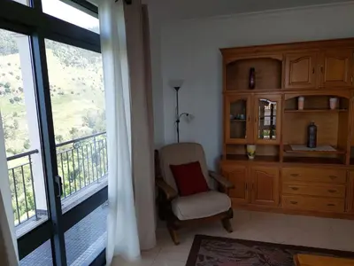 a living room with a chair and a large window at Casa do Vale da Estrela in Calheta