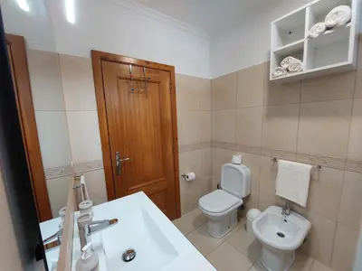 a bathroom with a white toilet and a sink at Casa do Vale da Estrela in Calheta