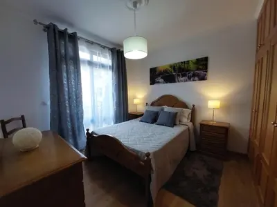 a bedroom with a bed and a table and a window at Casa do Vale da Estrela in Calheta