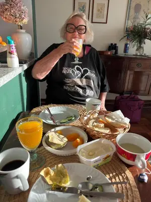 a woman sitting at a table drinking a glass of orange juice at Apartment Palma Madeira wandern und tauchen in Caniço