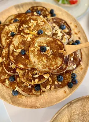 a wooden plate of pancakes with blueberries and nuts at Sunday Morning Guesthouse in Aljezur