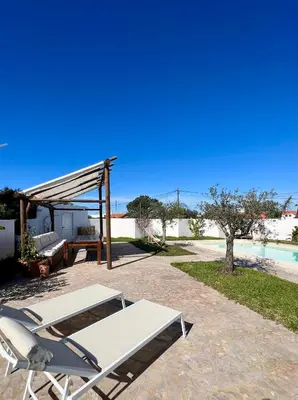 a lounge chair and a table next to a pool at Sunday Morning Guesthouse in Aljezur