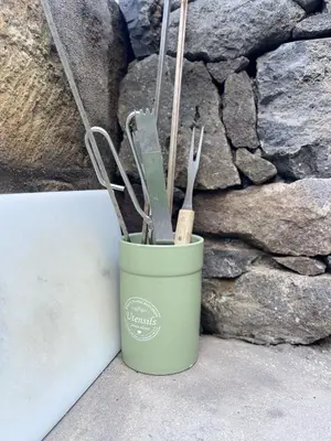 a green cup with utensils in it next to a wall at Casa do mar in São Vicente