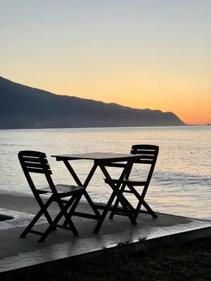 a picnic table and two chairs sitting next to the ocean at Casa do mar in São Vicente